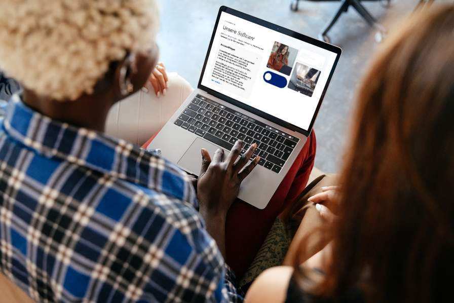 Zwei Frauen schauen auf einen Laptopbildschirm.